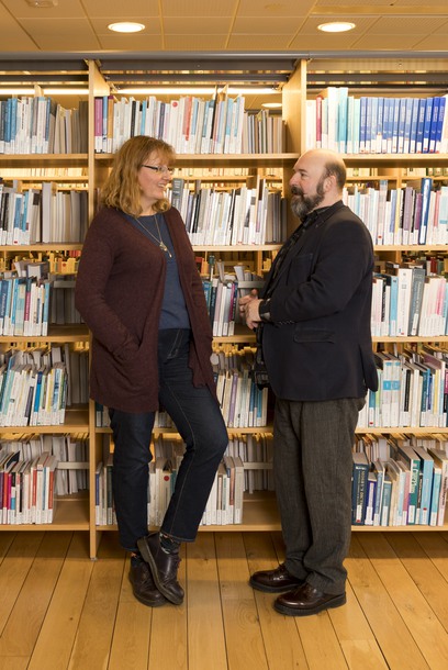 Anna Fåhraus och Jörgen Öijervall framför bokhyllor fyllda med böcker.