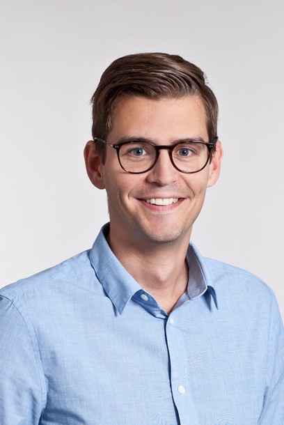 Porträttbild på en ung man i skjorta och glasögon.