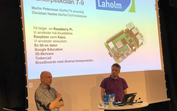 2 män pratar programmering framför stor skärm