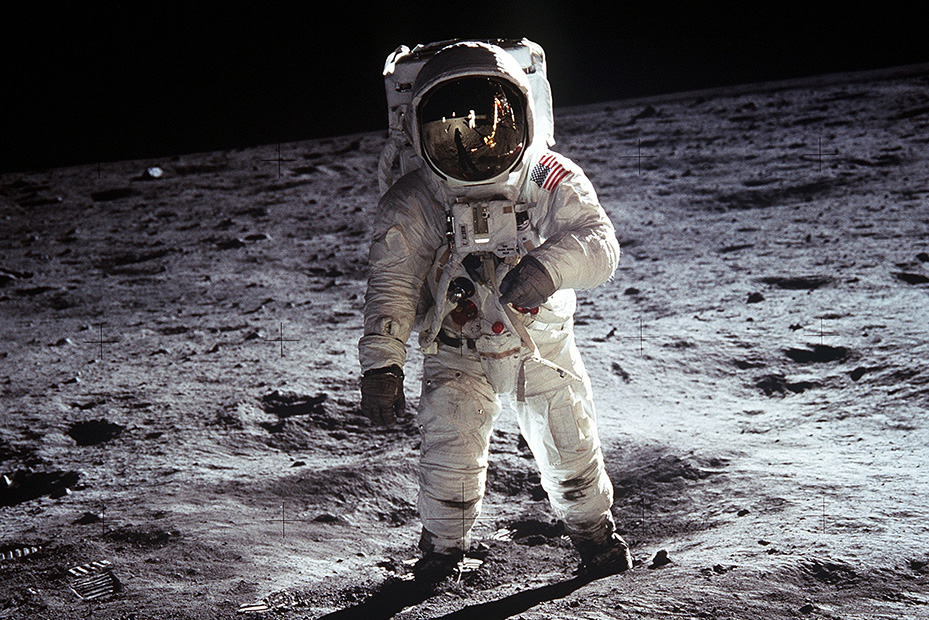 En astronaut står på en yta täckt av grå stoft. 