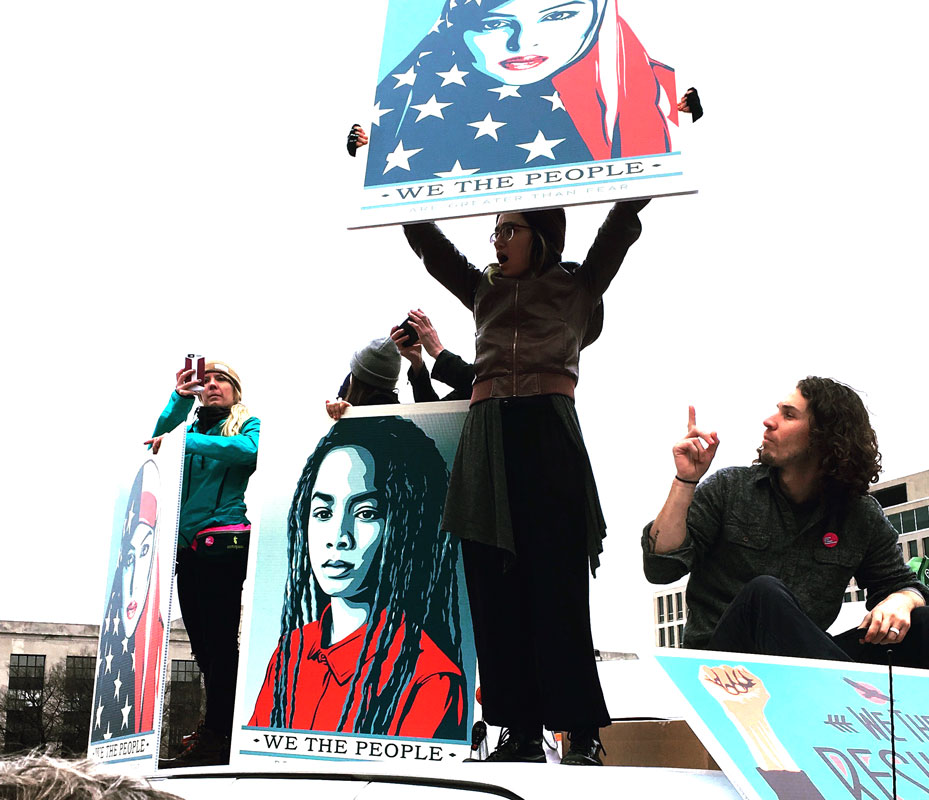 Demonstrationsbild, på olika skyltar bilder av en kvinna och texten We the people